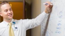 Alumni Patrick Halinsky uses a white board to map a process at a local hospital.