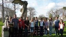 Students gather outside for a group photo in front of a winged statue