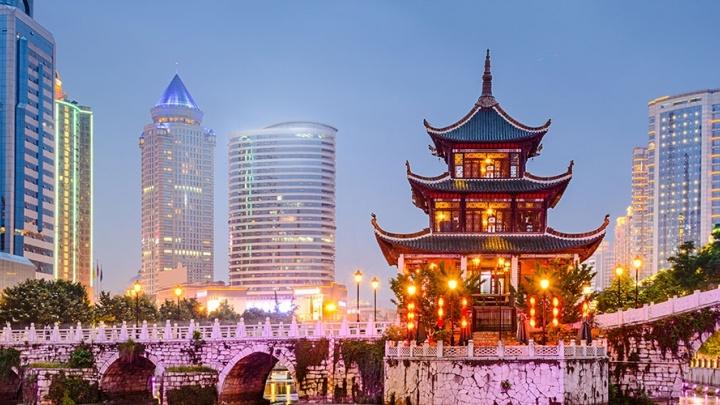 Traditional 中国人 building on a river in front of modern cityscape