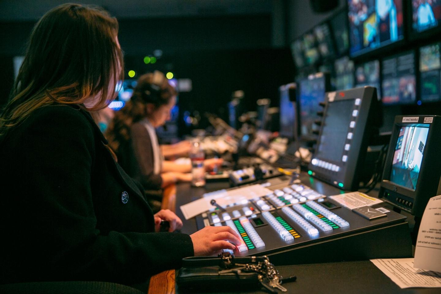 Students working in a tv control room with control boards and monitors