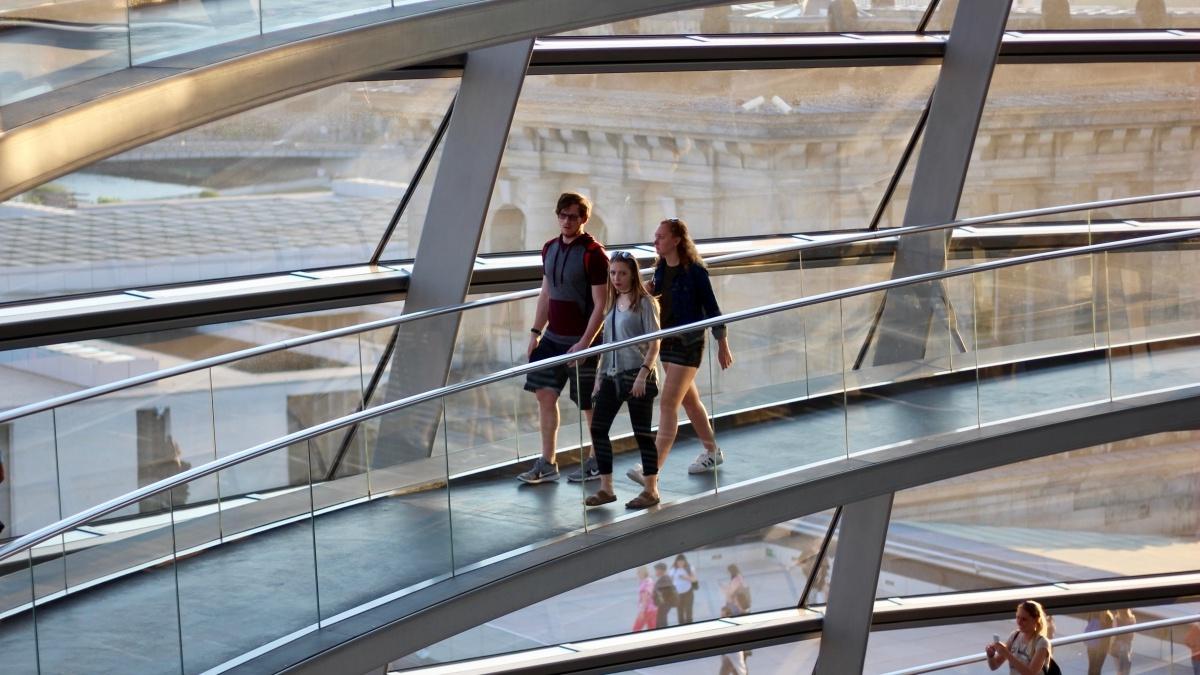 Students walking on indoor walkway with glass wall behind them